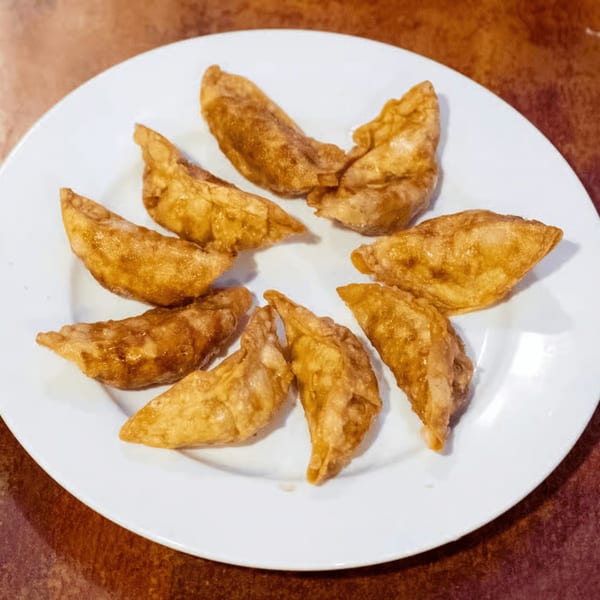 A white plate holds eight golden-brown, crispy fried dumplings from August Moon Chinese restaurant.